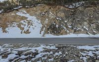 the car drives down a snowy road as a large rock is above it and on the side