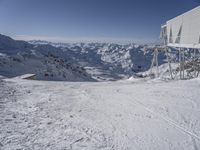 a person standing on skis in the snow under a building with a view of mountains