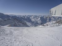 a person standing on skis in the snow under a building with a view of mountains