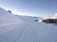 a ski slope with tracks left by skiiers in the snow outside of a small building