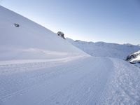 a ski slope with tracks left by skiiers in the snow outside of a small building