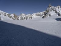 a person in the snow skiing and some rocks in the background that appear to be very high