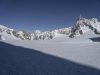 a person in the snow skiing and some rocks in the background that appear to be very high