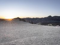 the sun is setting over a snowy landscape of rocks and boulders while a person takes a photograph in front