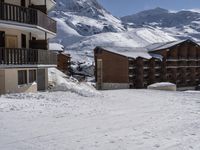 a couple of snow skis are sitting in the snow next to buildings and snow capped mountains