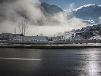 a red fire hydrant is sitting in the middle of a snow covered street with mountains behind it