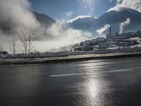 a red fire hydrant is sitting in the middle of a snow covered street with mountains behind it