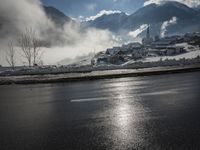 a red fire hydrant is sitting in the middle of a snow covered street with mountains behind it