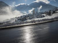 a red fire hydrant is sitting in the middle of a snow covered street with mountains behind it