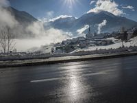 a red fire hydrant is sitting in the middle of a snow covered street with mountains behind it