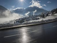 a red fire hydrant is sitting in the middle of a snow covered street with mountains behind it