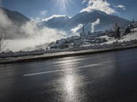 a red fire hydrant is sitting in the middle of a snow covered street with mountains behind it