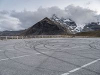 the mountains are snow covered with clouds and a curve in a parking lot on the edge of a hill