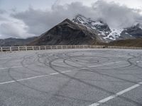 the mountains are snow covered with clouds and a curve in a parking lot on the edge of a hill