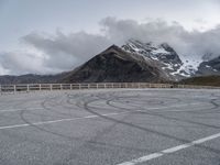 the mountains are snow covered with clouds and a curve in a parking lot on the edge of a hill