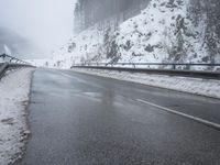 a car drives down a snowy, winding mountain road on a rainy day and it looks like it is about to fall