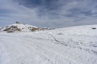 a road in the middle of snowy mountains near a mountaintop with a lighthouse on the top