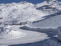 a road going through a mountain covered in snow with mountains behind it, and a sign in the foreground says stop