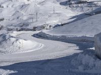 a road going through a mountain covered in snow with mountains behind it, and a sign in the foreground says stop