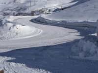 a road going through a mountain covered in snow with mountains behind it, and a sign in the foreground says stop