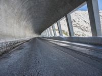 a car traveling down a snow covered mountain road between two large buildings under an overpass