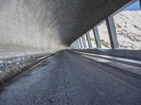 a car traveling down a snow covered mountain road between two large buildings under an overpass
