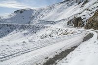 a snowy mountain road with a few people on it that is very wide and high