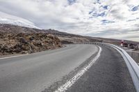 a road in the middle of nowhere with a lot of snow on the ground and a snowy mountain