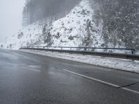 a car is driving down the road covered in snow near a snowy mountain top and mountain
