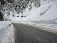 the snow on the side of a snowy mountain slope is covered in snow next to an asphalt road