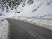 the snow on the side of a snowy mountain slope is covered in snow next to an asphalt road