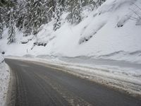 the snow on the side of a snowy mountain slope is covered in snow next to an asphalt road