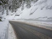the snow on the side of a snowy mountain slope is covered in snow next to an asphalt road