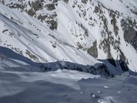 a man walking up the side of a snow covered mountain slope as someone skis