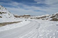 a dirt road near the snowy mountains covered in snow near the bottom of the hill