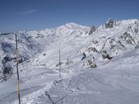 two mountains covered with snow in the distance while a skier skis down a slope