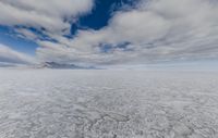 white snow is floating through a blue sky over mountains in the background, with clouds