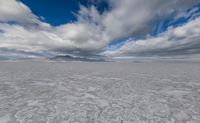 white snow is floating through a blue sky over mountains in the background, with clouds