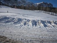 there is snow covered ground by a road in the mountains on a sunny day on a clear day
