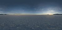 a snow covered mountain side with sun peeking over the horizon on top of it is a landscape view with large snowy mountains, snow flake, bright and sparse sand - like terrain, and bright clouds