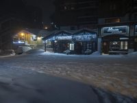 a building and some lights in the snow by the street with it's cars