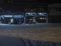 a building and some lights in the snow by the street with it's cars