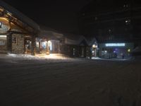 the exterior of a building on a snowy night in winter time with a lit up shop