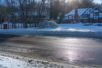 there is snow all over the ground by a road and some houses in the background