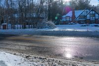 there is snow all over the ground by a road and some houses in the background