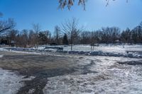 a park area covered with snow and ice covered ground and benches next to a fence