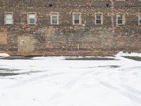 a parking lot with snow covered roads and windows in front of a brick building in the snow