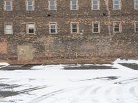 a parking lot with snow covered roads and windows in front of a brick building in the snow
