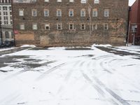 a parking lot with snow covered roads and windows in front of a brick building in the snow