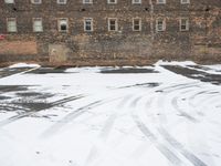 a parking lot with snow covered roads and windows in front of a brick building in the snow
